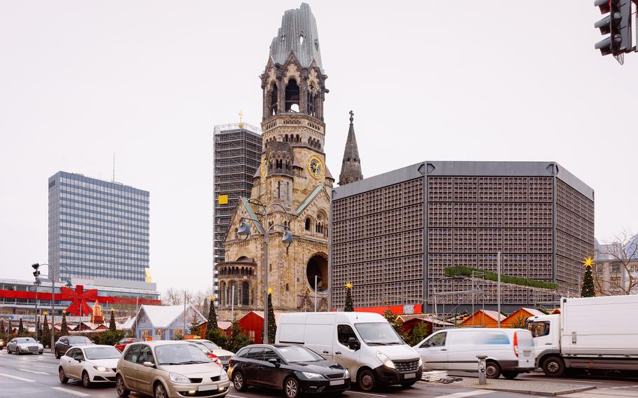 The historic church stands in contrast with a modern city and traffic passing by