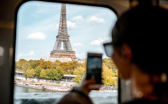 Young woman photographing with smartphone Eiffel tower from the subway train in Paris. Image focused on the tower
