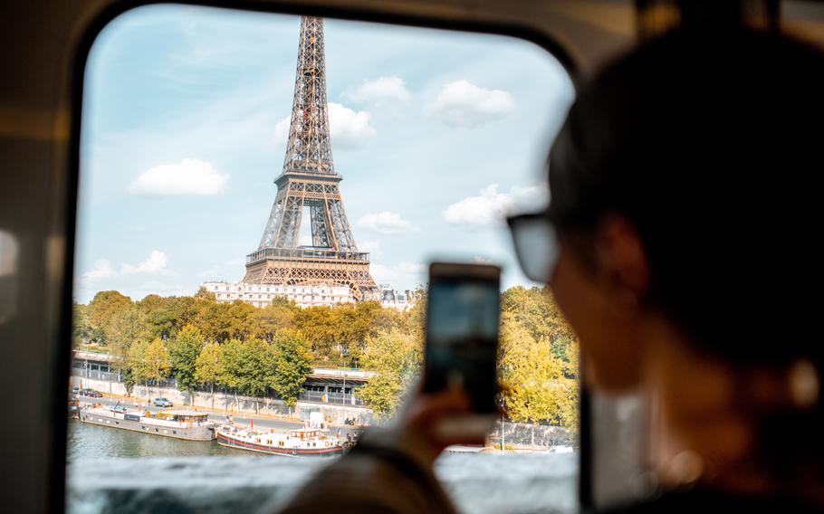 Young woman photographing with smartphone Eiffel tower from the subway train in Paris. Image focused on the tower