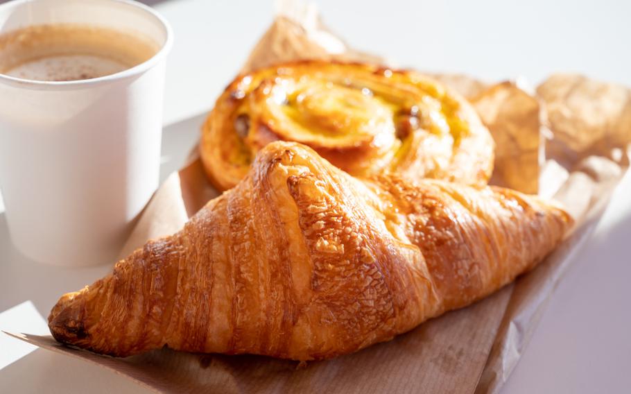 Breakfast in bakery served outdoor, cups of coffee and fresh baked croissants and pastry, morning food close up
