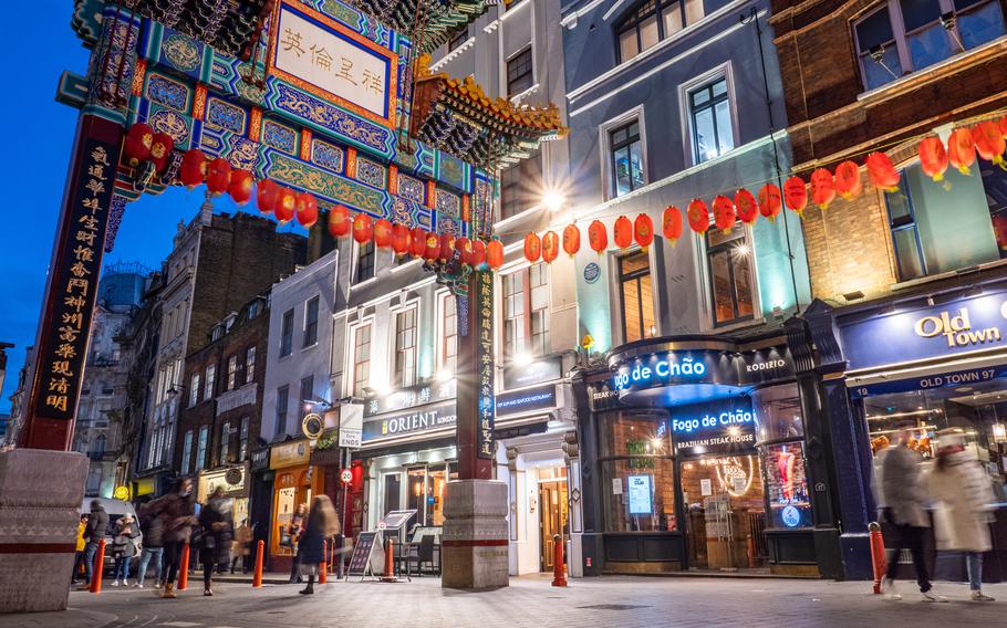 Chinatown, London, at dusk with tourists passing through the landmark gate.