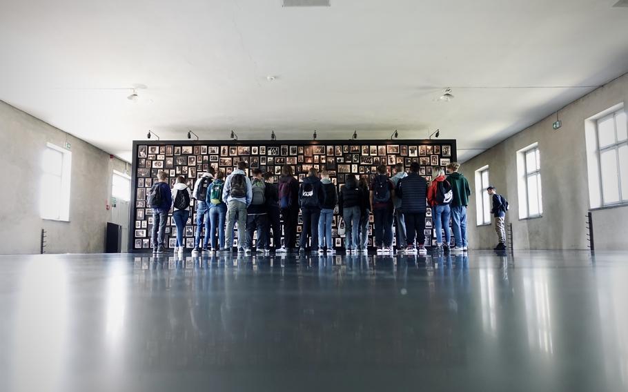 This poignant image depicts a memorial exhibit inside the Auschwitz-Birkenau Memorial and Museum. A wall filled with photographs of Holocaust victims stands as a haunting tribute to the lives lost, each image representing a story of hope, family, and humanity. The stark simplicity of the room amplifies the emotional weight of the exhibit, serving as a powerful reminder of the importance of remembering and honoring the victims of this tragic chapter in history.