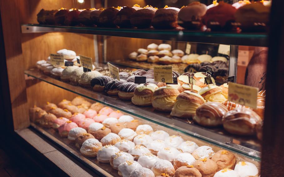 Assortment of doughnuts on cafe showcase. Variety of desserts with different flavours on shelves in store. Restaurant confectionery, bakery