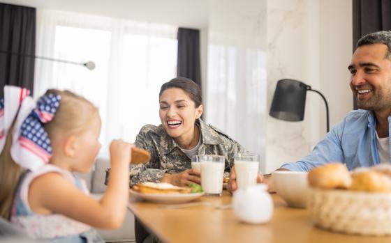 Daughter eating cookie. Appealing happy military woman laughing while looking at her daughter eating cookie