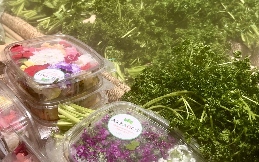 Purple and white edible flowers and green herbs in a grocery store