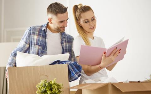 Photo Of Young couple moving in a new house and unpacking boxes with belongings