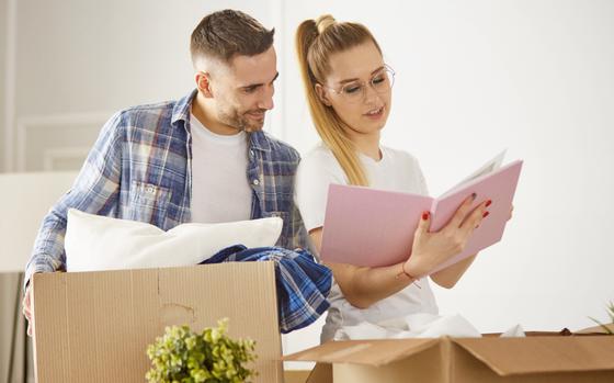 Young couple moving in a new house and unpacking boxes with belongings
