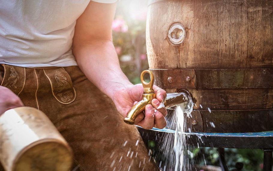 Man tapping into a wooden barrel with a wooden mallet.