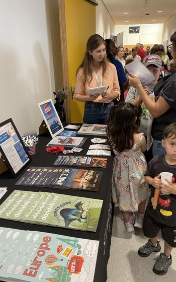 Table filled with colorful magazines and kids looking at them. 