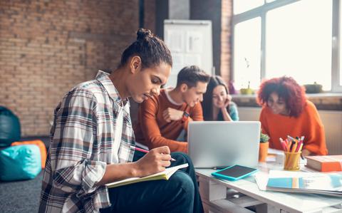 Photo Of Group of four students getting together to study with a laptop, notebooks and pencils.