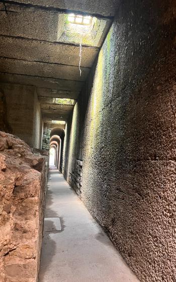 an underground view of the tunnel system of the Imperial bath ruins. light shines through the corridor and illuminates a reddish, sandy stone. 