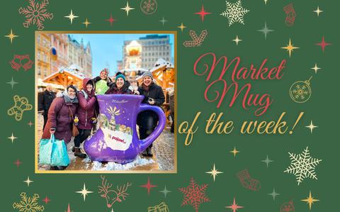 Photo Of A group of women circled around a giant, bright purple boot-shaped mug a the Christmas market. 