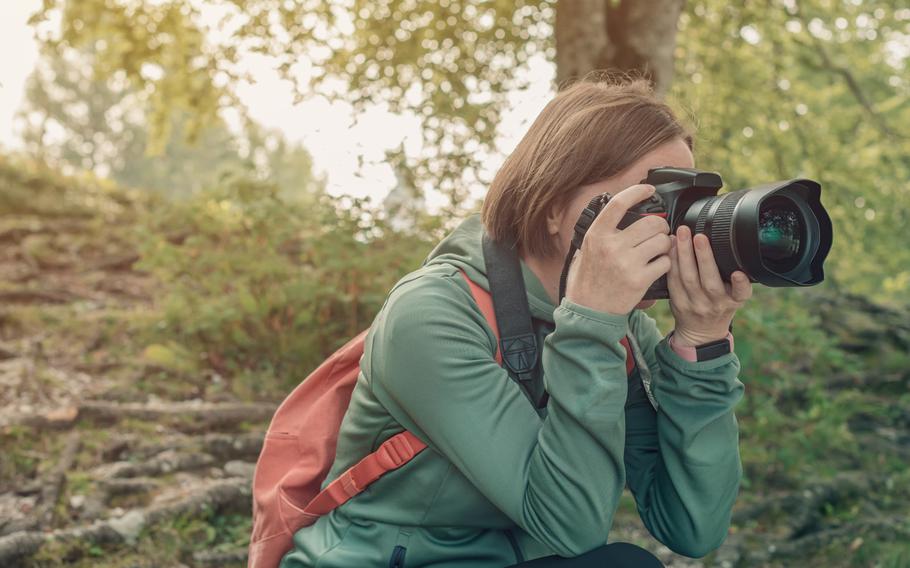 Female hiker and landscape photographer photographing nature with camera while trekking on summer vacation. 