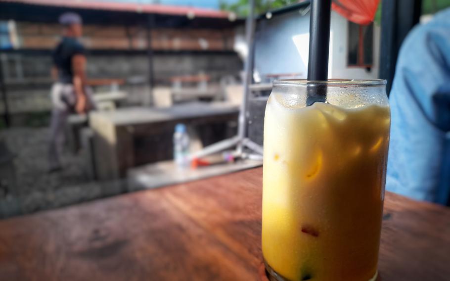 A yellow beverage in a glass on a restaurant table with a blurred background.
