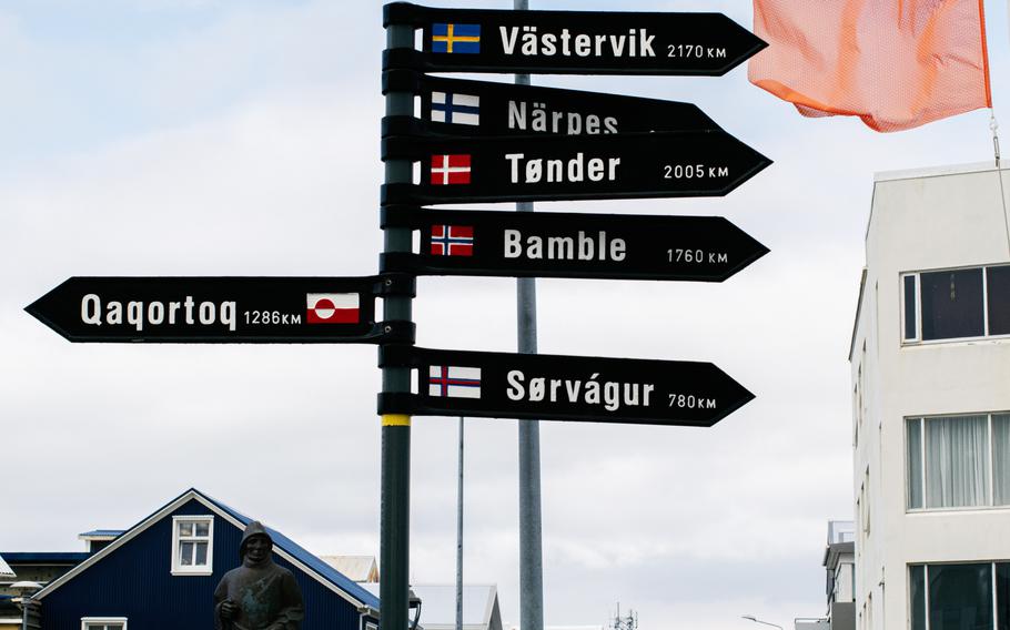 A detailed signpost in Akranes pointing to locations with distances and flags.