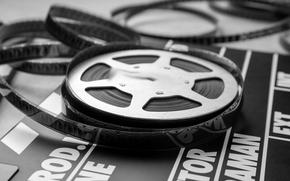 Movie clapper and film reel on table, closeup