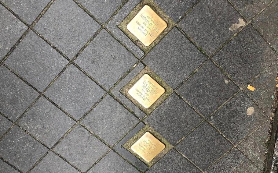 Three gold Holocaust memorial tiles on the ground