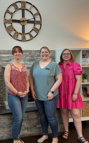 Three Spouse Hub volunteers standing in front of the fireplace