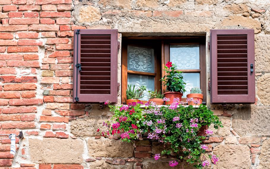 Monticchiello, Italy town or village city in Tuscany and closeup of open window shutters and pink purple flower decorations on sunny summer day nobody architecture wall