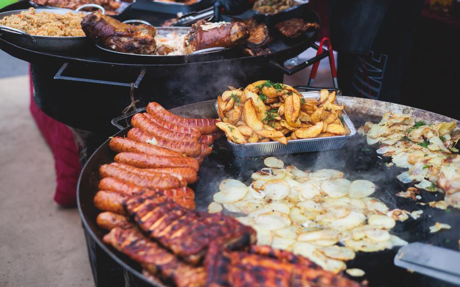 Food festival with food stall kiosk, open-air outdoor fair market, assortment of different traditional European grilled barbecued street food with sausages, bbq, chicken, pork and lamb on a large pan