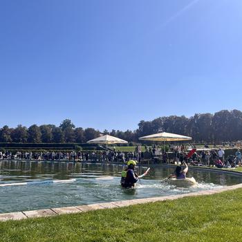 a bright blue pool of water with a girl paddling a large hollowed-out pumpkin. 