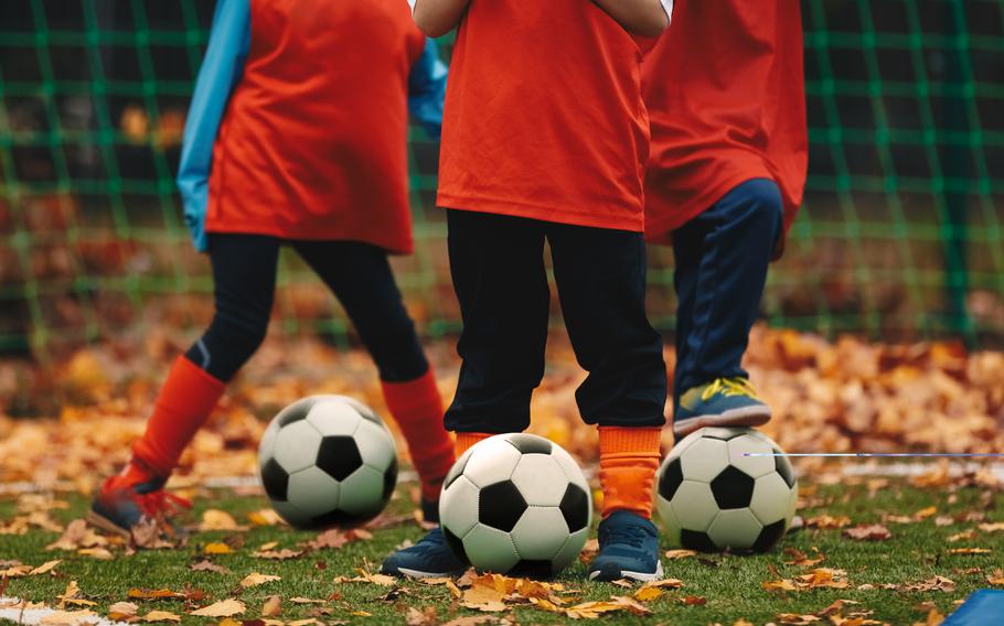  Soccer players with ball on grass field covered with autumn leaves