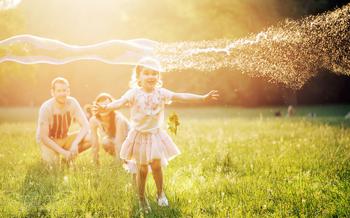 Happy family blowing a bubbles in a summer park