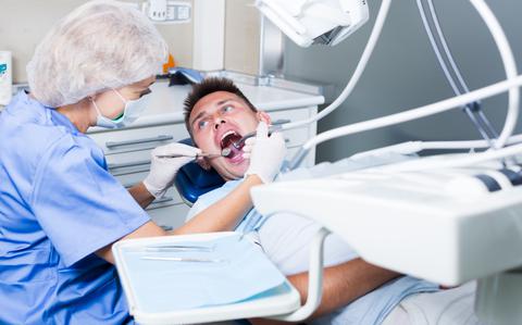 Photo Of Dentist and patient in dental office. Focus on young male patient