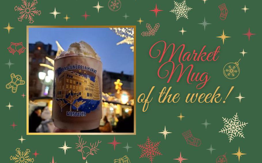 An up-close photo of a frosted market mug with blue and gold detailing of the city and lilies, filled with hot chocolate and whipped-cream. 