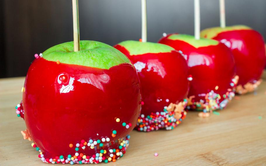 A delightful row of shiny, candy-coated apples, each adorned with colorful sprinkles, ready to add a touch of sweetness to any celebration. 