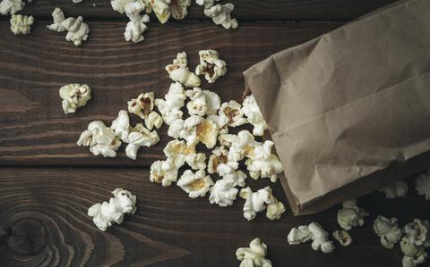 Photo Of Popcorn in paper bag on wooden table