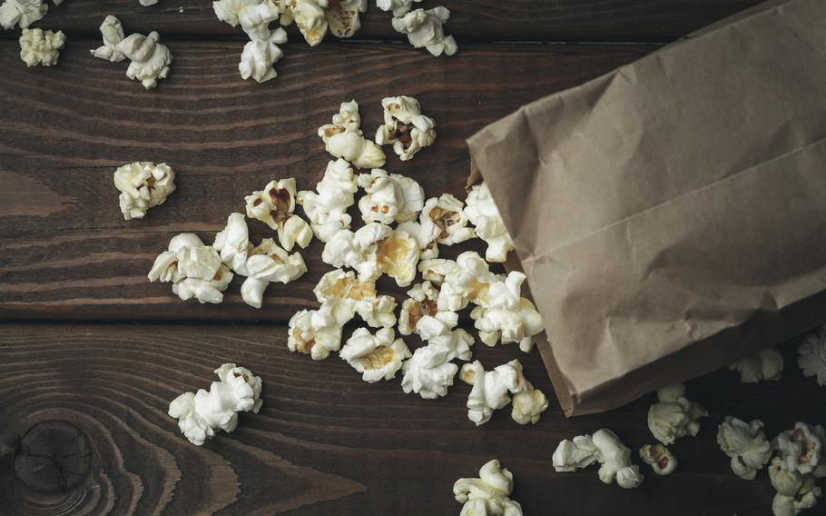 Popcorn in paper bag on wooden table