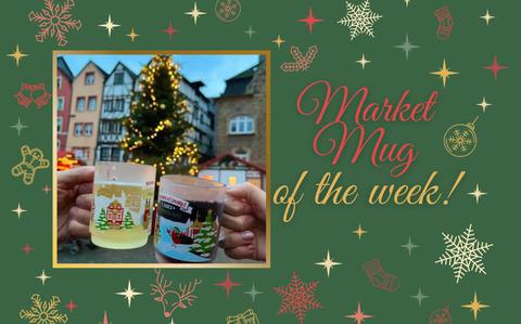 Photo Of Two hands cheers two frosted market mugs against the backdrop of a twinkling Christmas tree and half-timbered houses