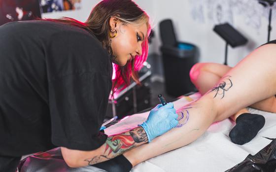 Tattoo artist using the Freehand technique to draw a tattoo on a leg