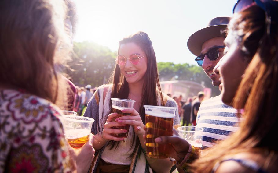 At a sunny summer festival, friends gather, sharing cold beers and laughing. 