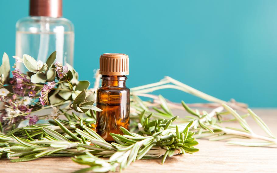 Bottle with aromatic oil and rosemary on a wooden table