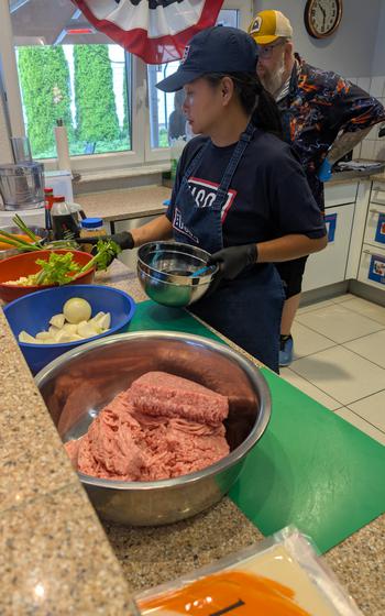 Row of food ingredients sitting on a counter with volunteers prepping 