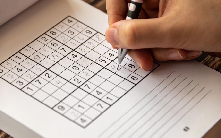 Person solving a sudoku puzzle.