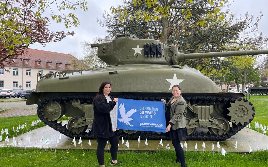 Two women standing infront of tank