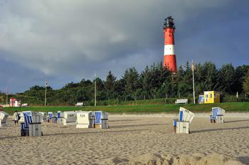 The lighthouse of Hornum behind chairs on the sandy beach area