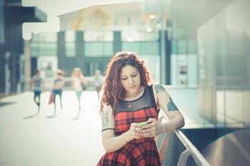 Tattooed girl looking down at phone