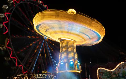 Photo Of bright neon yellow, spinning ride and red lit-up Ferris wheel against night sky. 