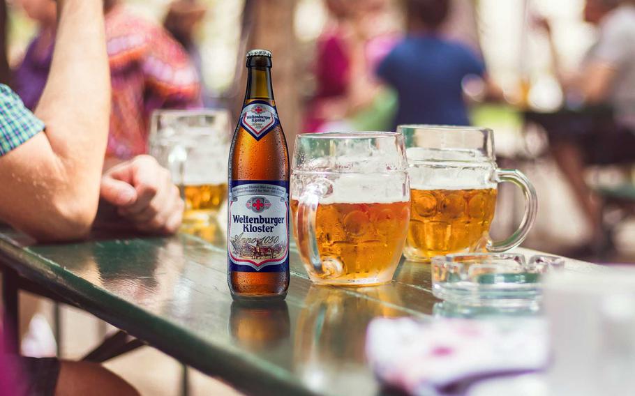 Bottle of Kloster beer in a table with larger glass mugs at a German beer garden.