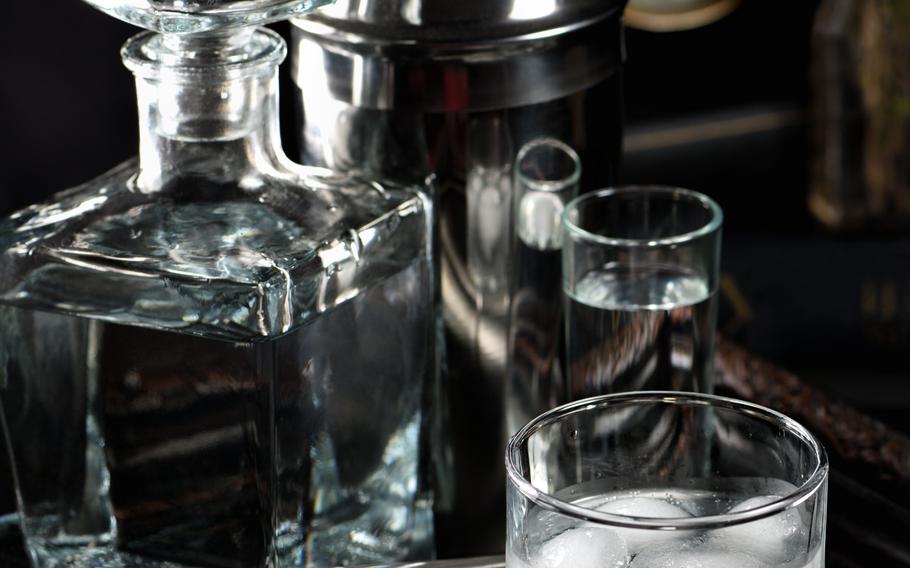 A glass of gin and tonic cooled with ice on a tray standing on the books