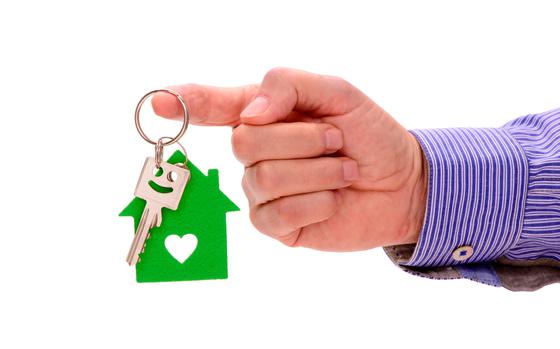 Keychain in the form of a house in a hand on a white background isolation