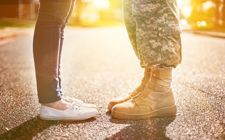 Close-up of the legs of a military member in boots and a person in jeans and white flat shoes