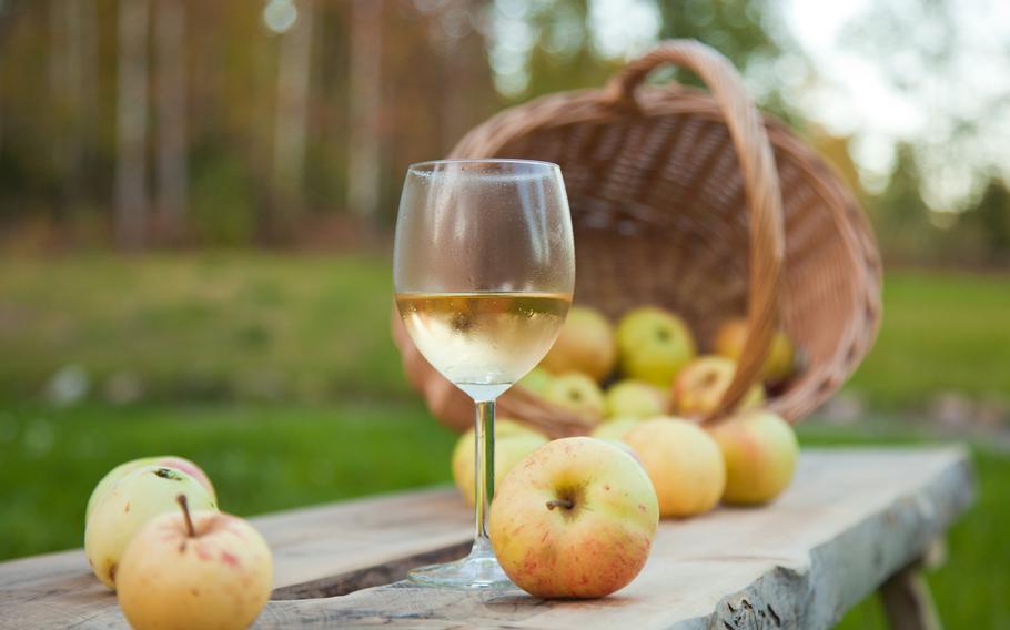 Apple drink in a chilled wine glass, rustic settings with apples and wicker basket