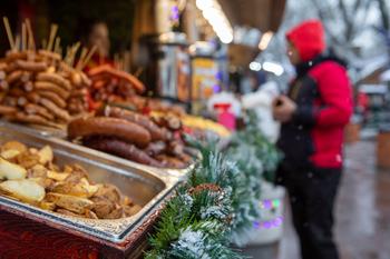 Close-up of a festive plate with sausage and potatoes, garnished with holiday decorations.