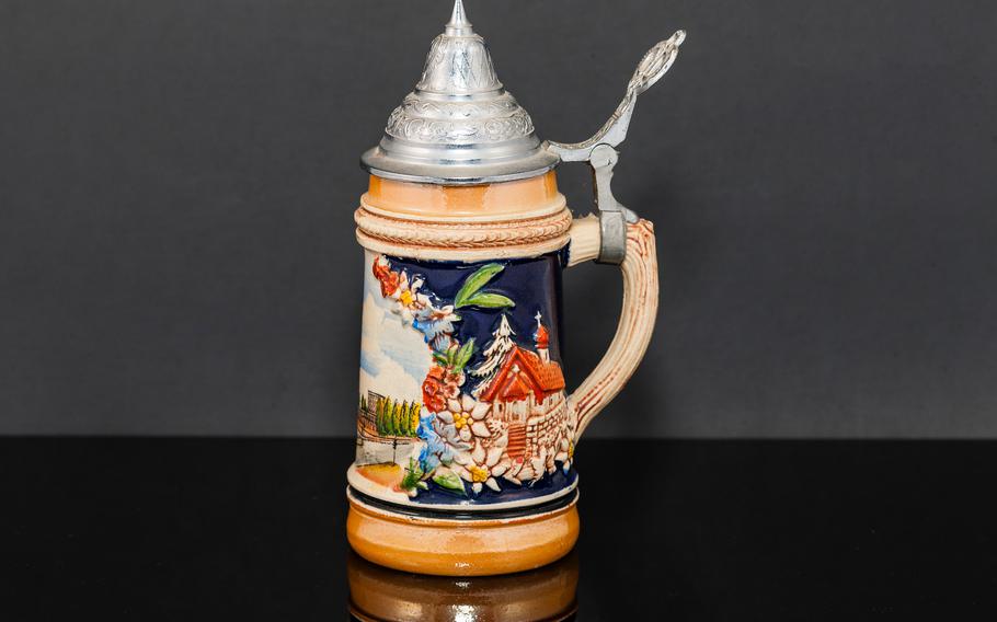 the left side of a German beer stein souvenir from the 1950’s adorned with flowers and a house