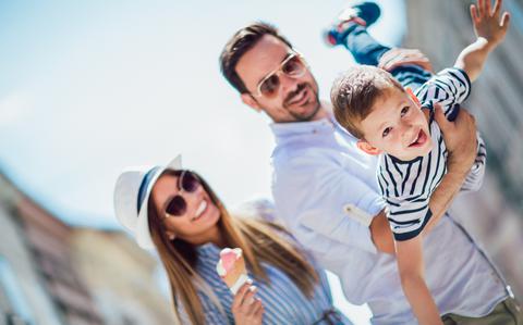 Photo Of Women is holding ice cream cone and looking at man holding a young boy who has his arms stretched out as if he is flying like a plane